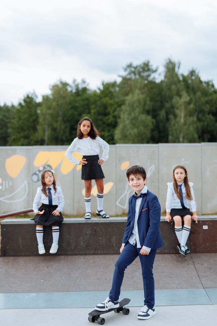 Kids in stylish school uniforms at a skatepark, showcasing youthful energy.